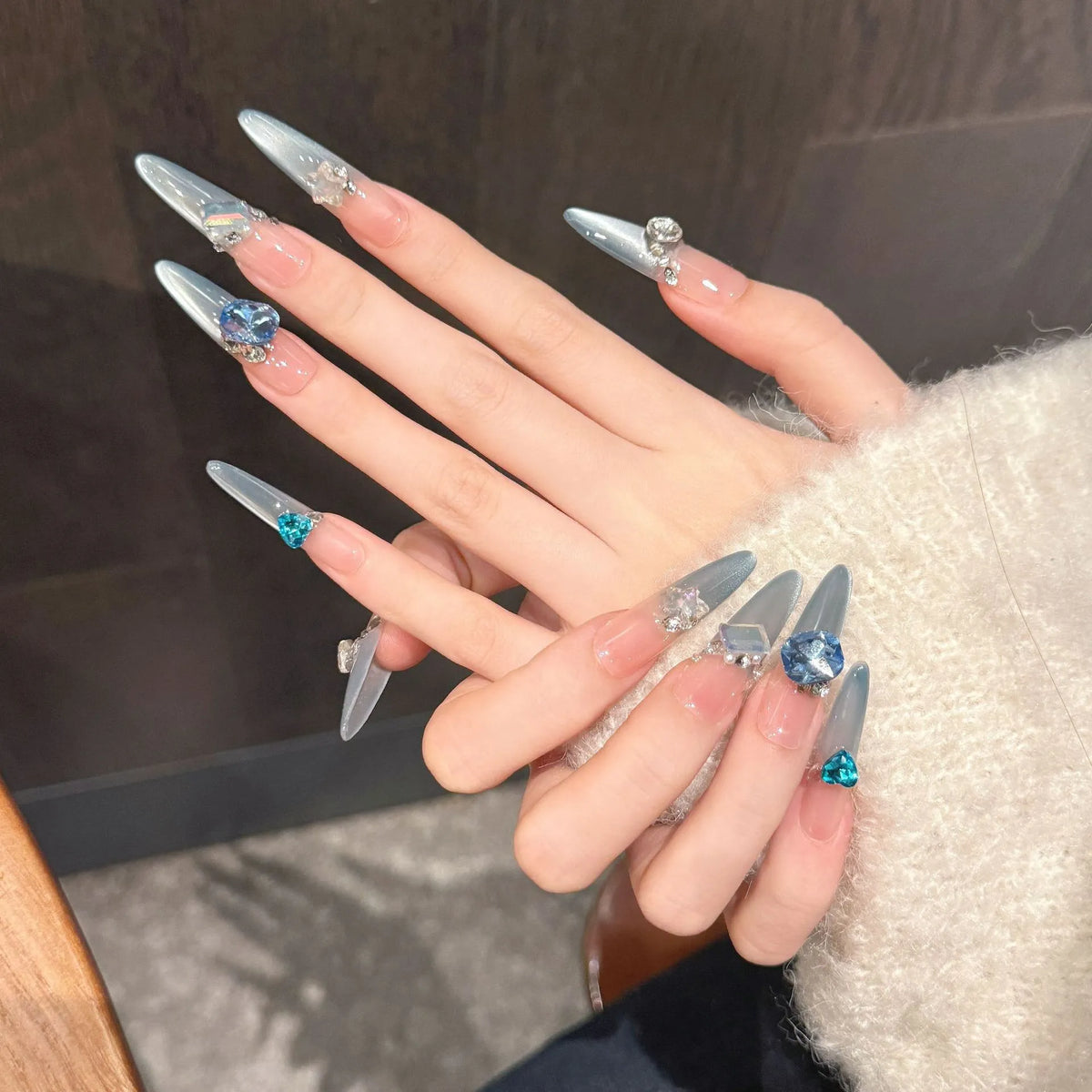 Blue Danube long stiletto press-on nails with ice blue gradient and sapphire crystals on hand - lifestyle shot