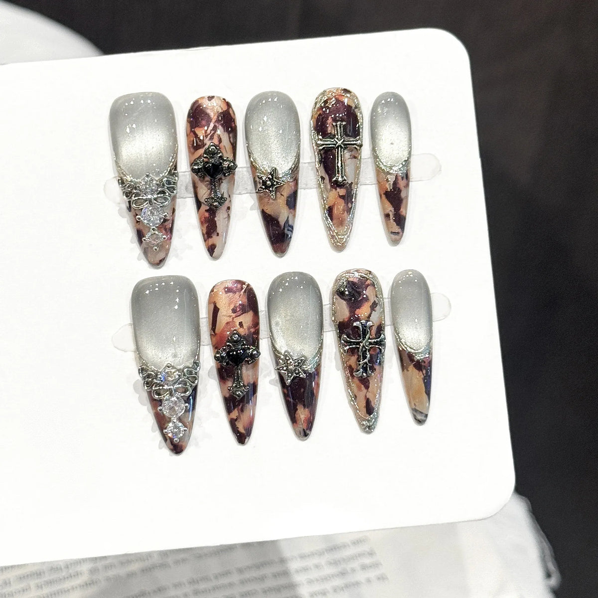 Antique Relic long stiletto press-on nails with brown cat-eye shimmer and vintage cameo design on hand - lifestyle shot