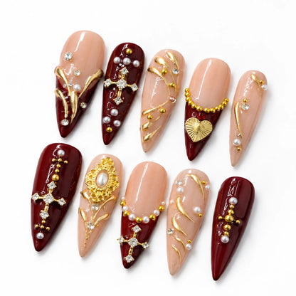 Angled view of blush nude and burgundy Long Stiletto nails with crystal crosses and pearl accents
