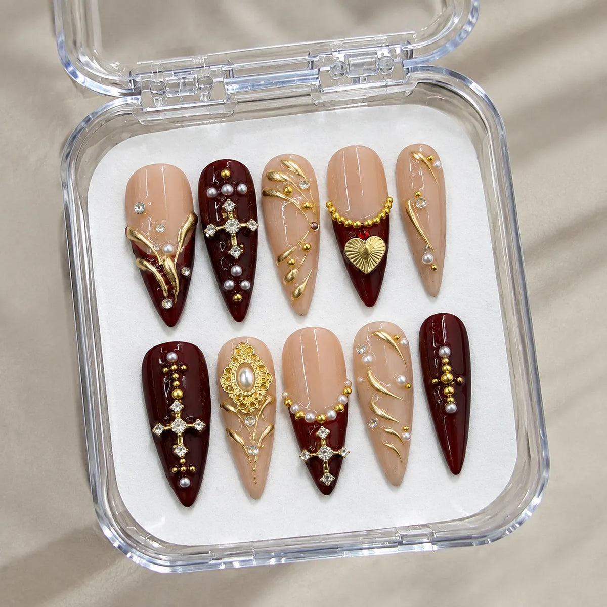 Burgundy Reliquary handmade Long Stiletto nail set arranged in a clear presentation case