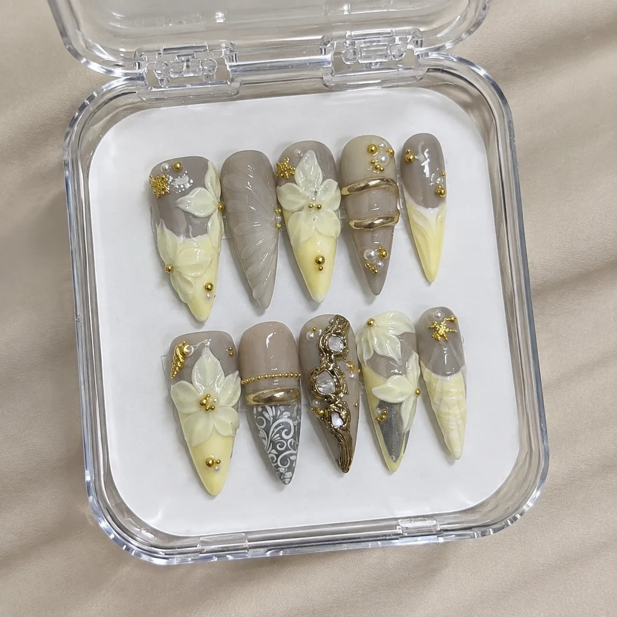 Buttercream Fleur handmade Long Stiletto nail set arranged in a clear presentation case