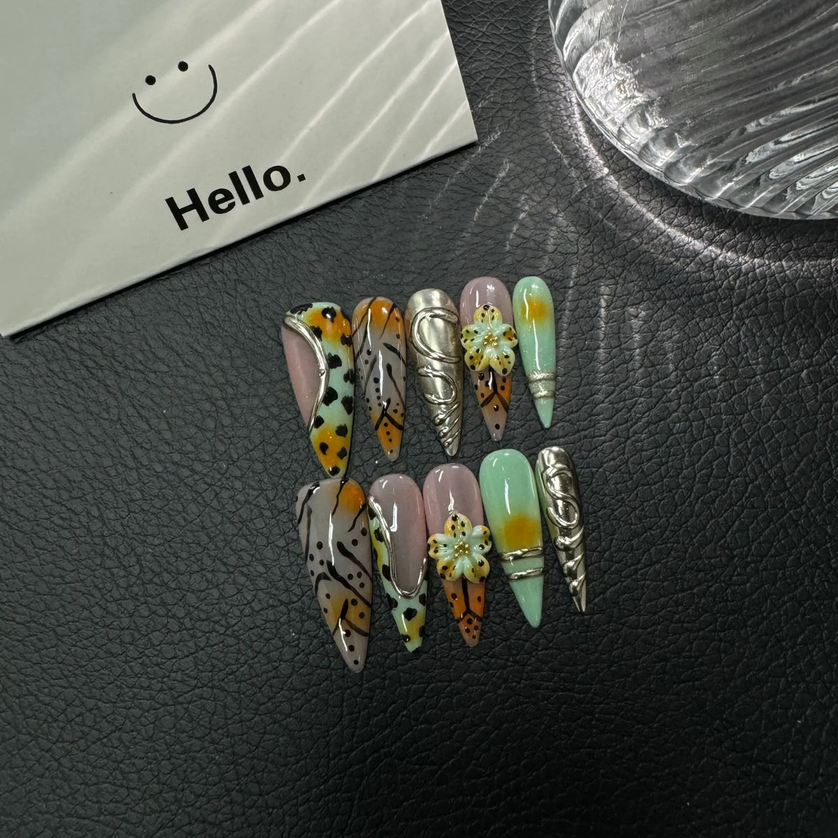 Lifestyle flat lay of mint orange black and silver NM-Z189 Long Stiletto press-on nails