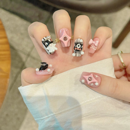 Devil Heart short coffin press-on nails worn on a hand with pink bows, ghosts and striped Halloween art