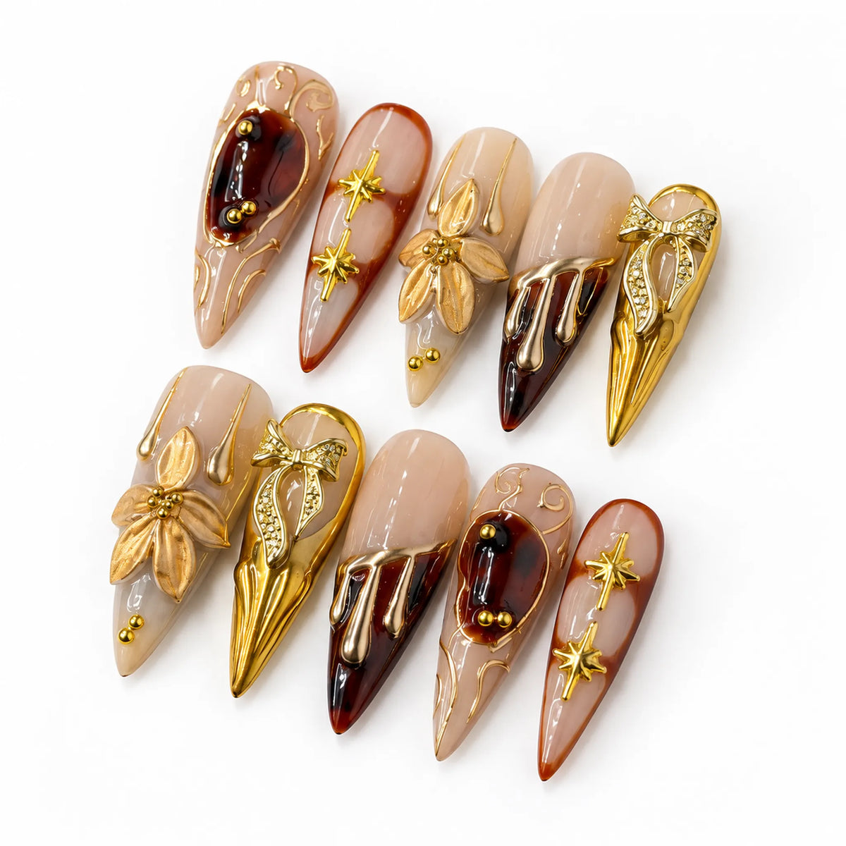 Angled view of nude and wine Long Stiletto nails with sculpted gold florals jeweled bows and metallic drips