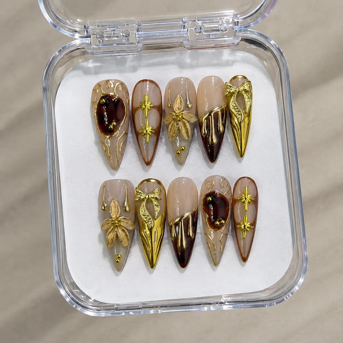 Gilded Court Fleur handmade Long Stiletto nail set arranged in a clear presentation case
