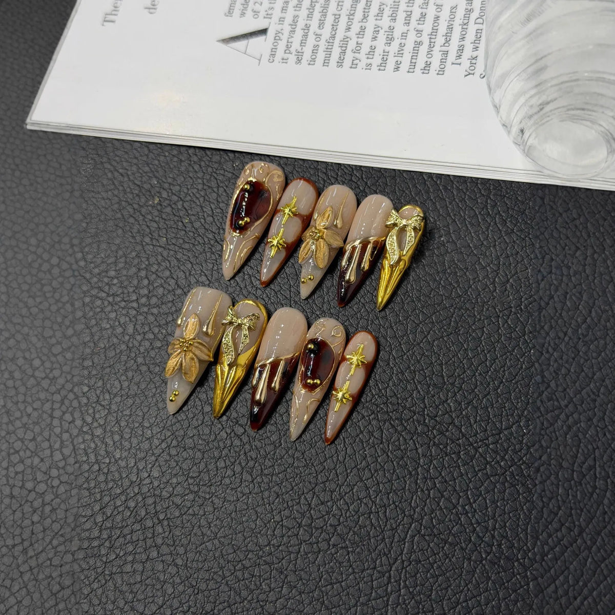 Lifestyle flat lay of NM-C123 nude wine and gold Long Stiletto press-on nails