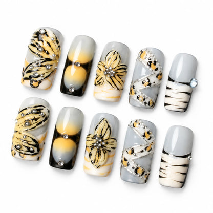 Angled view of gray and yellow Medium Coffin nails with butterfly art leopard ribbon and silver details