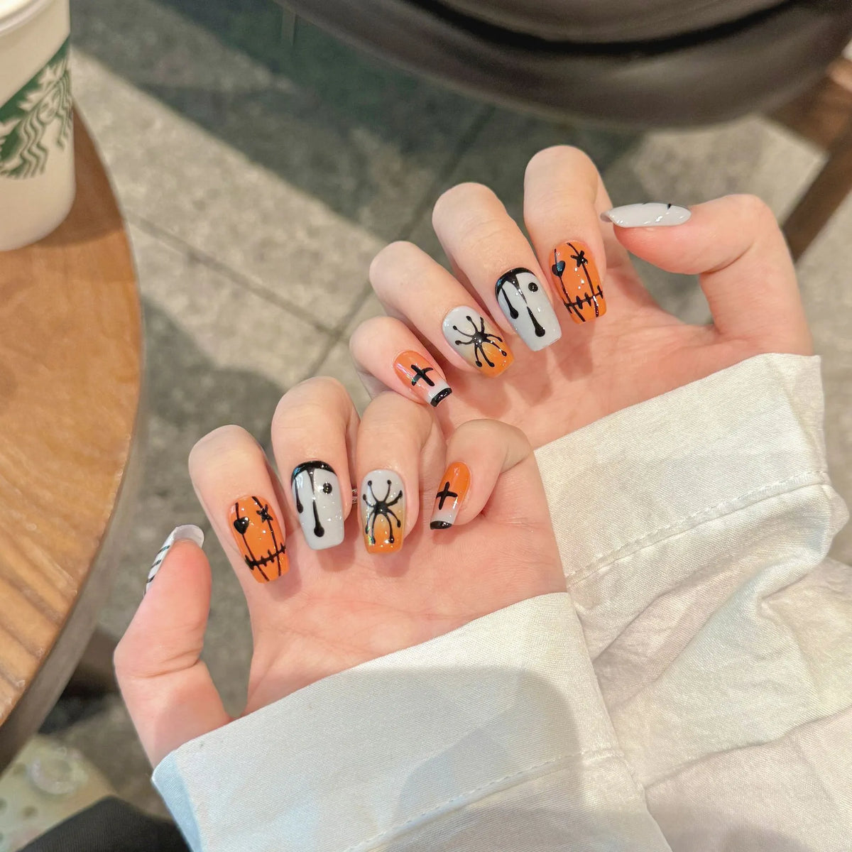 Halloween Stitch Spider short coffin press-on nails worn on hands with stitched orange and gray details