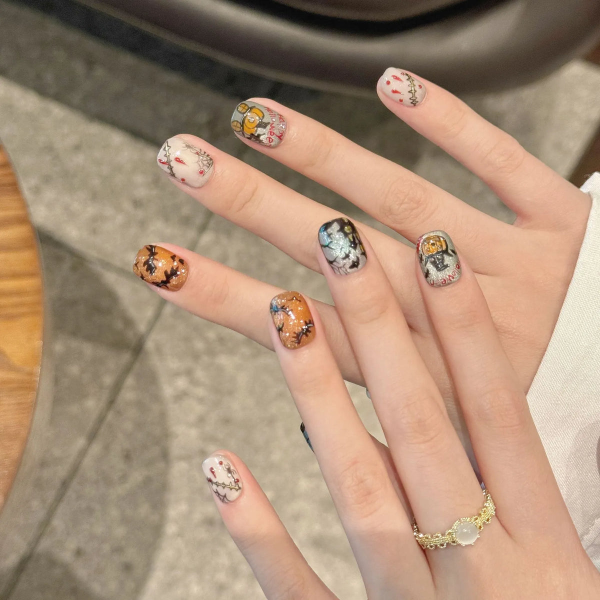 Haunted Moon 2373 Short Oval press-on nails worn on hands with pumpkins, bats, webs, and stitched details