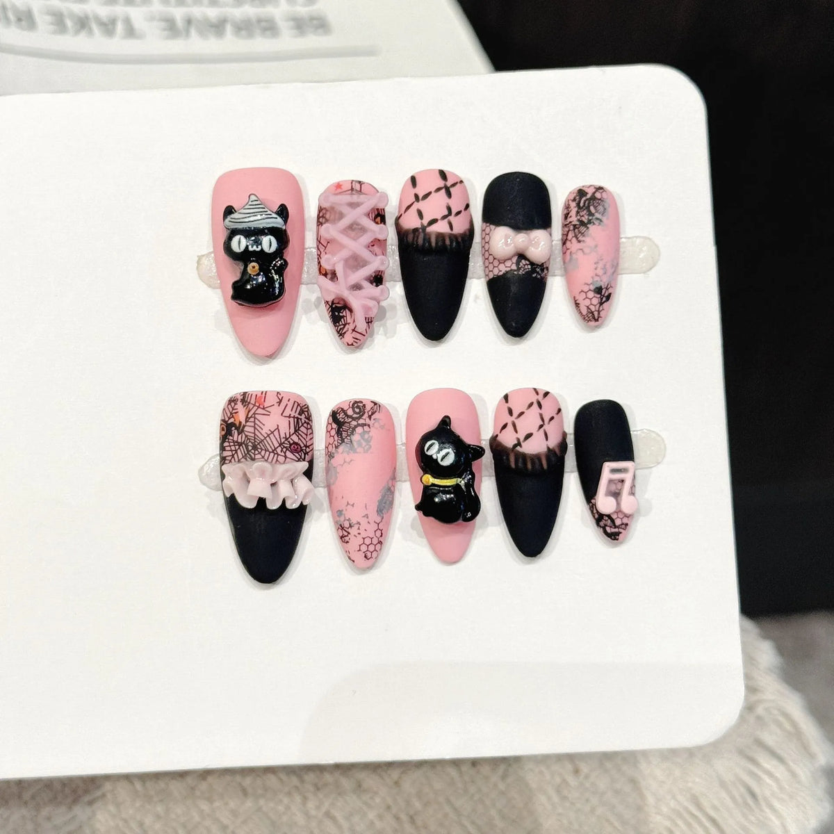 Honey Cat almond press-on nails with black pink cat music note lace bow sweet design on hand - lifestyle shot 🐱🎀