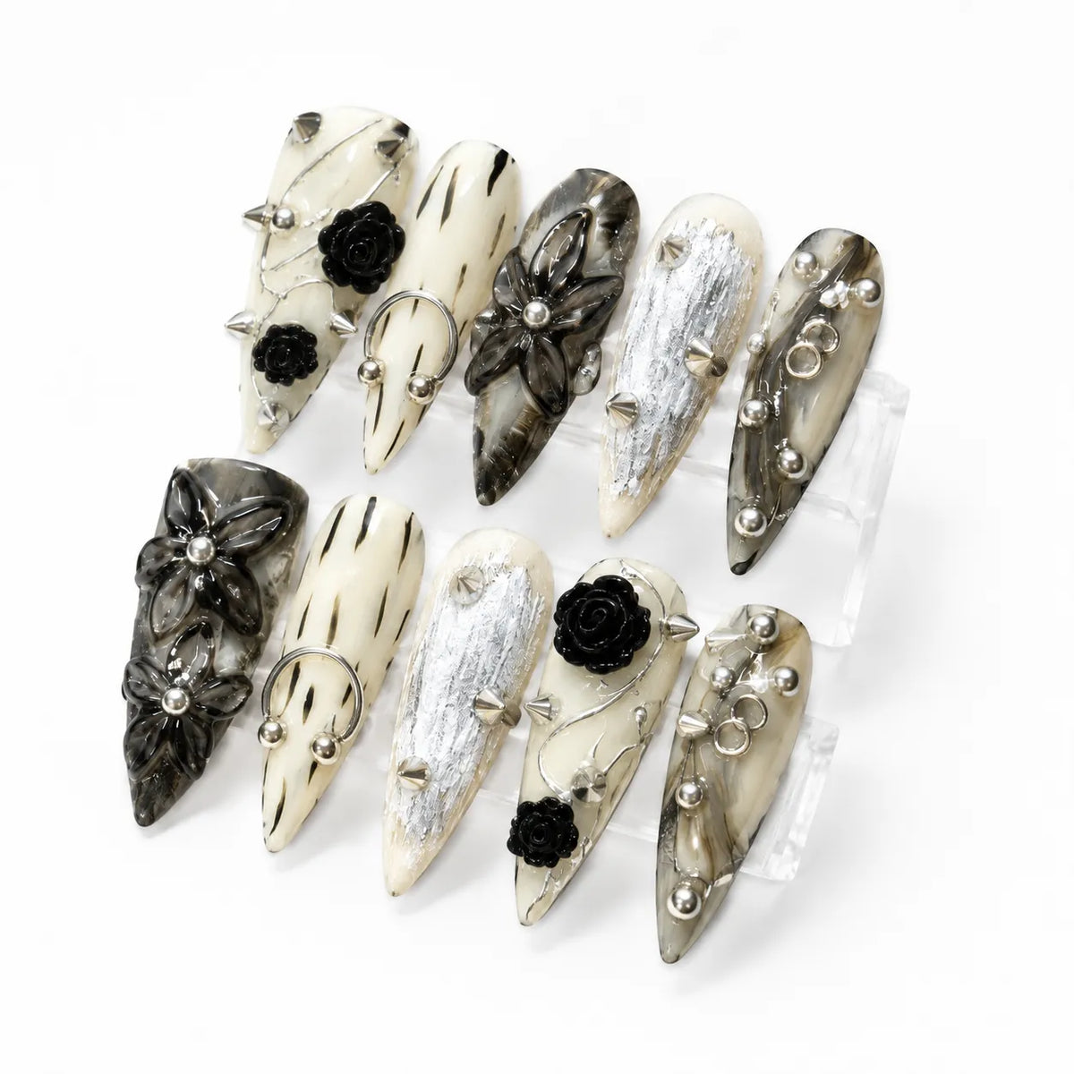 Angled view of Inkthorn Noir punk nails showing raised black roses, metal rings, studs, and silver foil