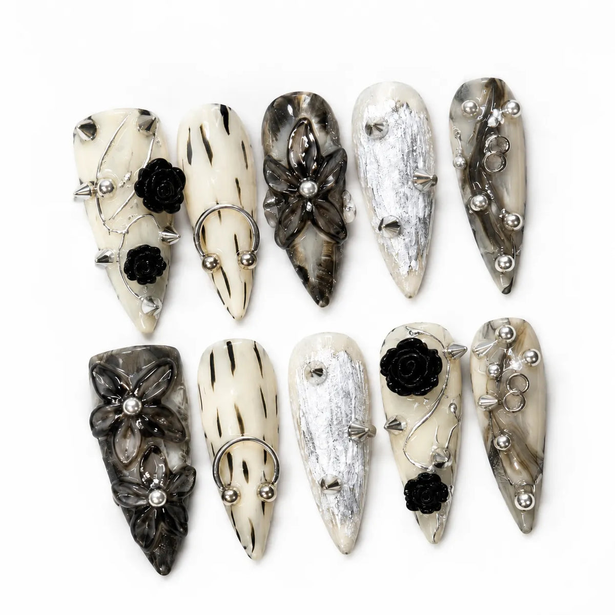 Flat lay of Inkthorn Noir Long Stiletto nails with smoky ink wash, black flowers, and silver hardware