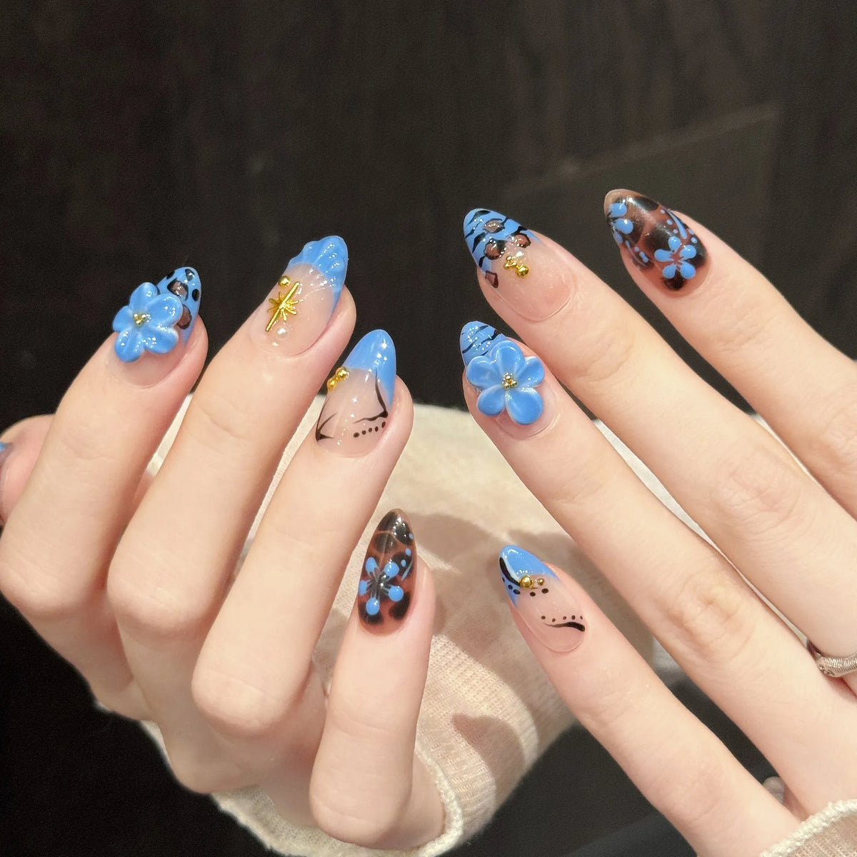 Leopard Lagoon oval nails angled view showing periwinkle blue gradient, leopard print, and 3D embellishments