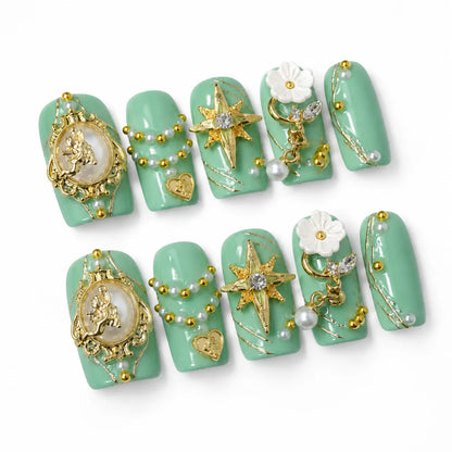 Angled view of mint-green Medium Coffin nails with gold angel cameos pearl garlands and crystal stars