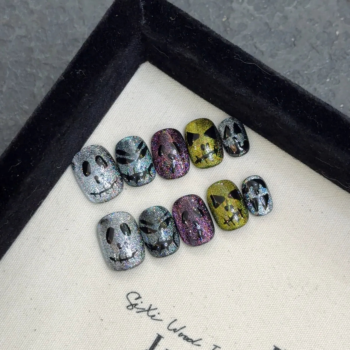 Close-up of rainbow cat-eye glitter and little-devil artwork on short oval nails 2054