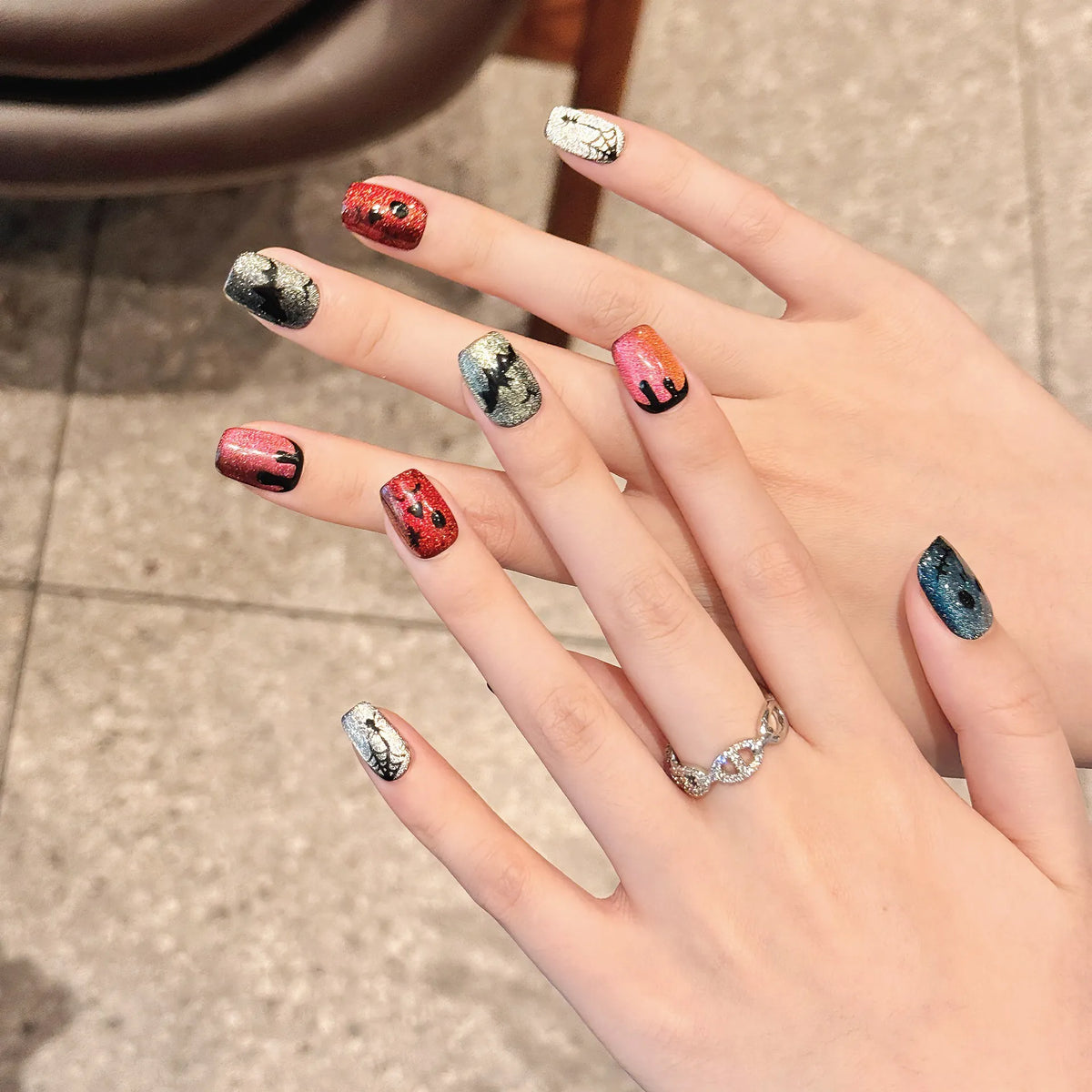 Rainbow devil cat-eye Short Coffin press-on nails 2329 worn on a hand with red, blue, silver, and pink shimmer