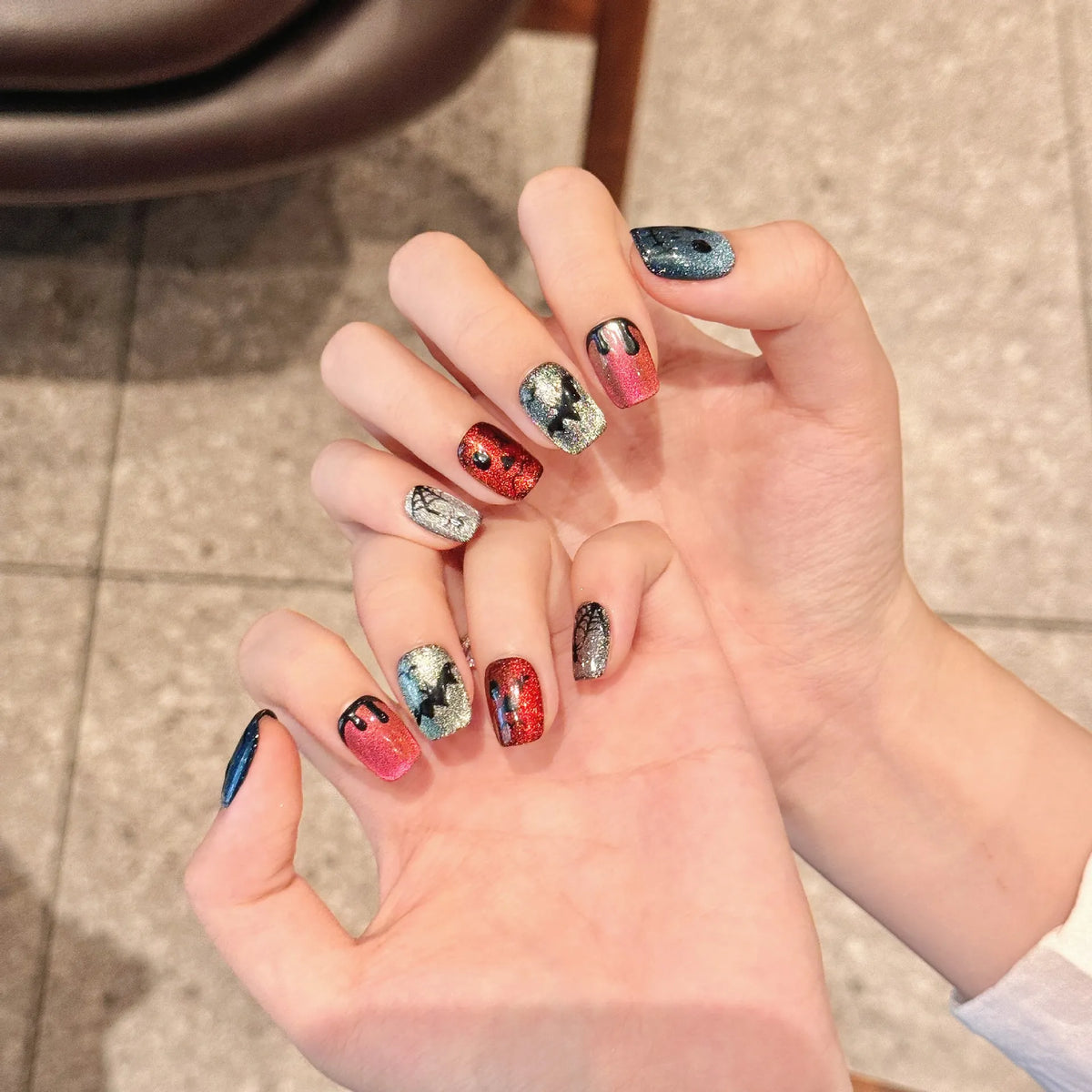 Rainbow devil cat-eye Short Coffin nails 2329 shown in a hand lifestyle view with Halloween devil artwork