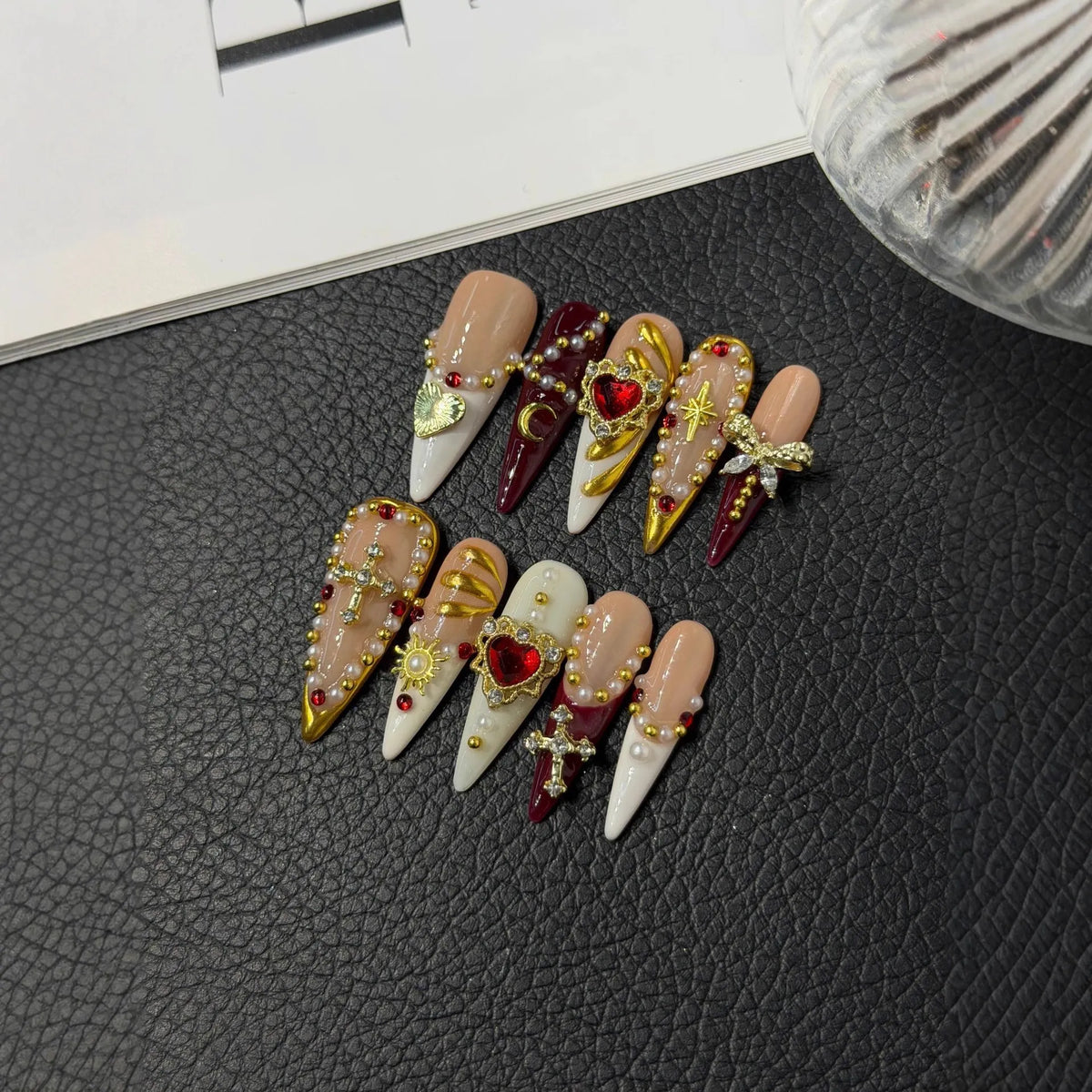 Lifestyle flat lay of NM-A026 blush wine and gold Long Stiletto press-on nails