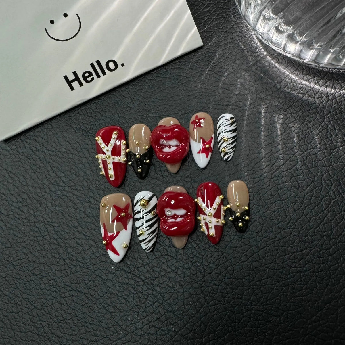 Detailed display of Scarlet Kiss Rebel Medium Almond nails with gold studs crystal tooth and color-block tips