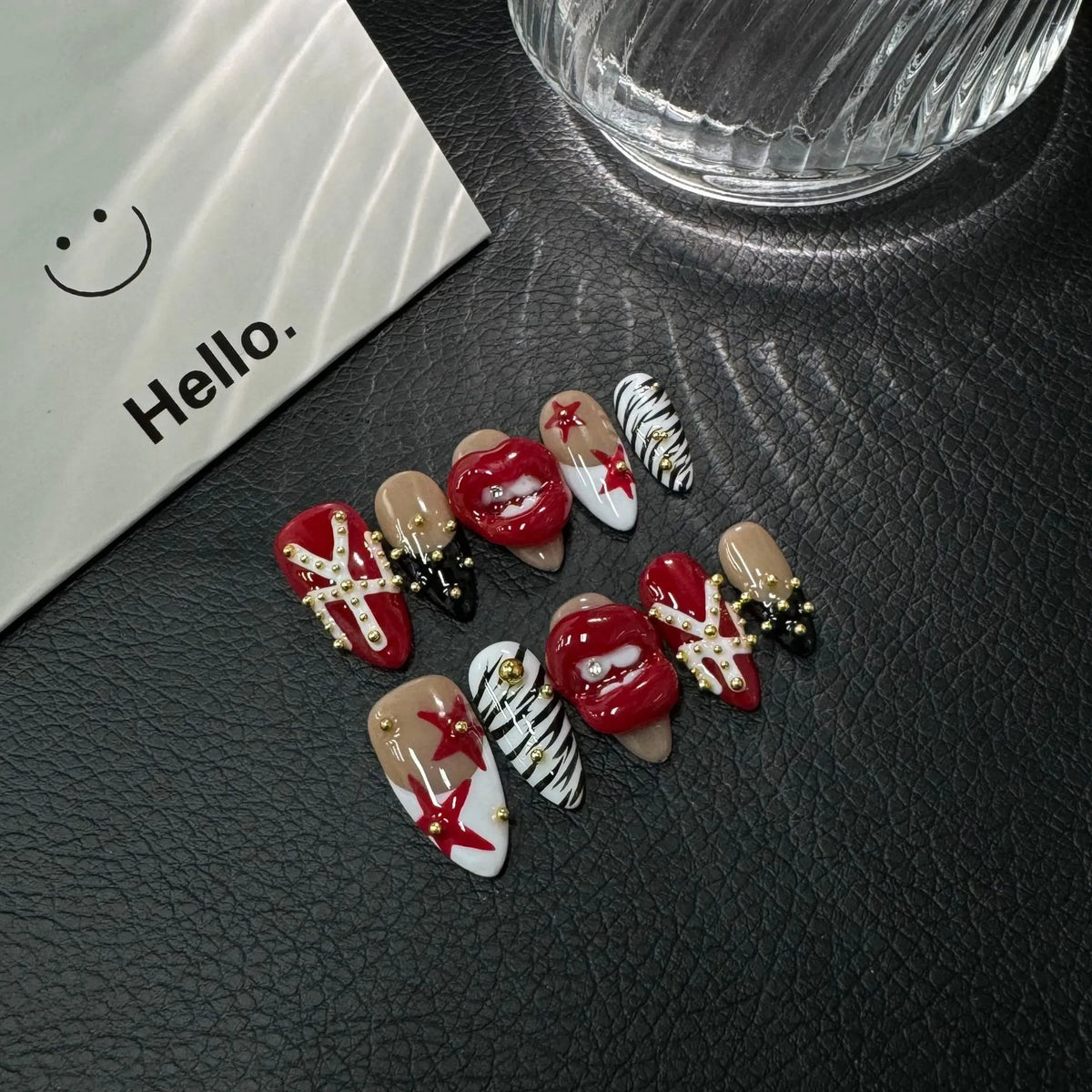 Lifestyle display of NM-C090 Medium Almond nails with dimensional red lips zebra print and stars